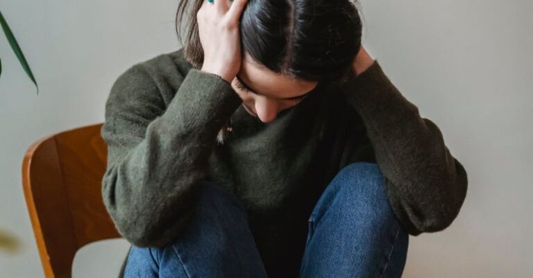 Concerns - Anxious young woman cover wing ears with hands sitting on chair