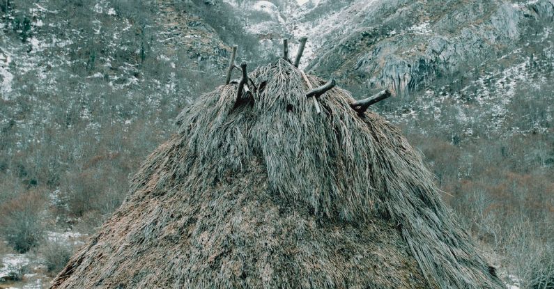 Anthropology - Old aboriginal stone wigwam with thatched roof located on snowy mountainous terrain in winter