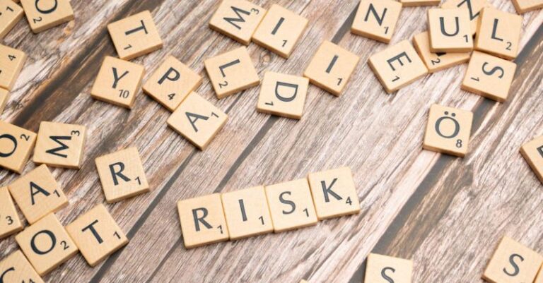 Factors - Scrabble letters spelling risk on a wooden table